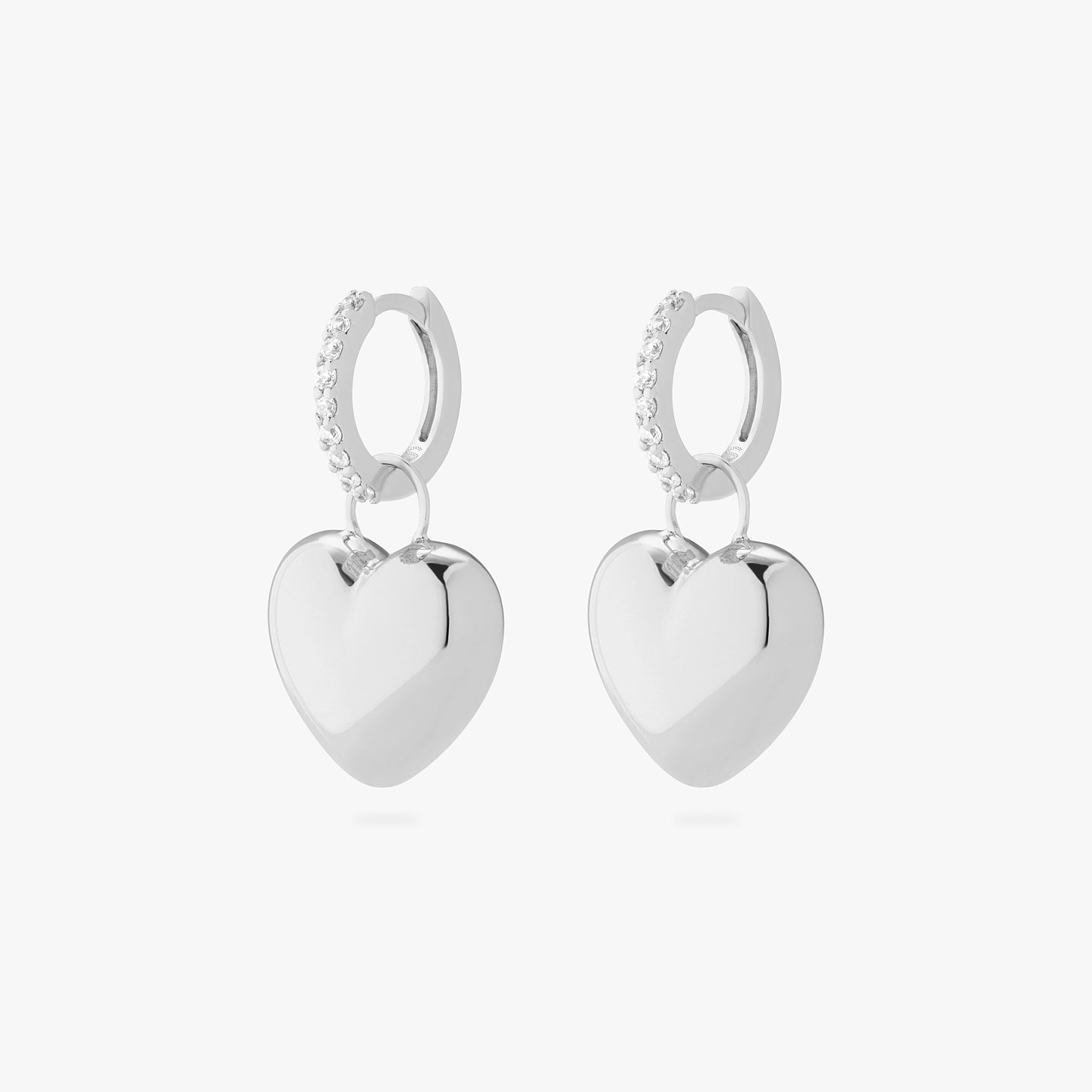An image of a pair of silver/clear mini pave huggies with silver, puffy heart shaped charms. [pair] color:null|silver/clear