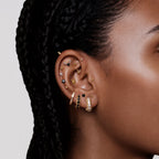 this image shows an earscape featuring the 14k gold plated max pave spike huggie. this huggie has clear cz stones and gold spikes up and down the sides 