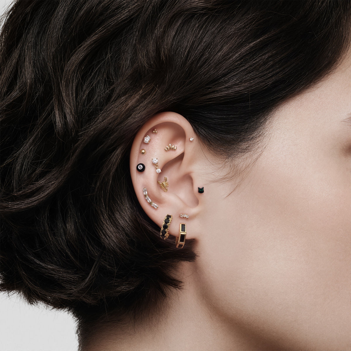 this image shows an earscape featuring the 14k gold plated max bezel baguette huggie with black cz baguette stones. 