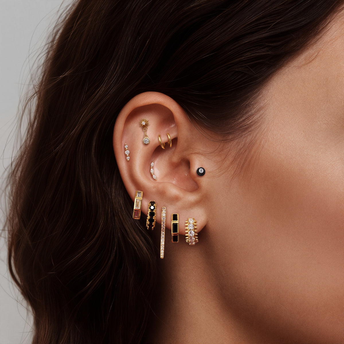 this image shows an earscape featuring the golden titanium 8 ball flatback with enamel. the outside of the ball is black and the inner circle is white 