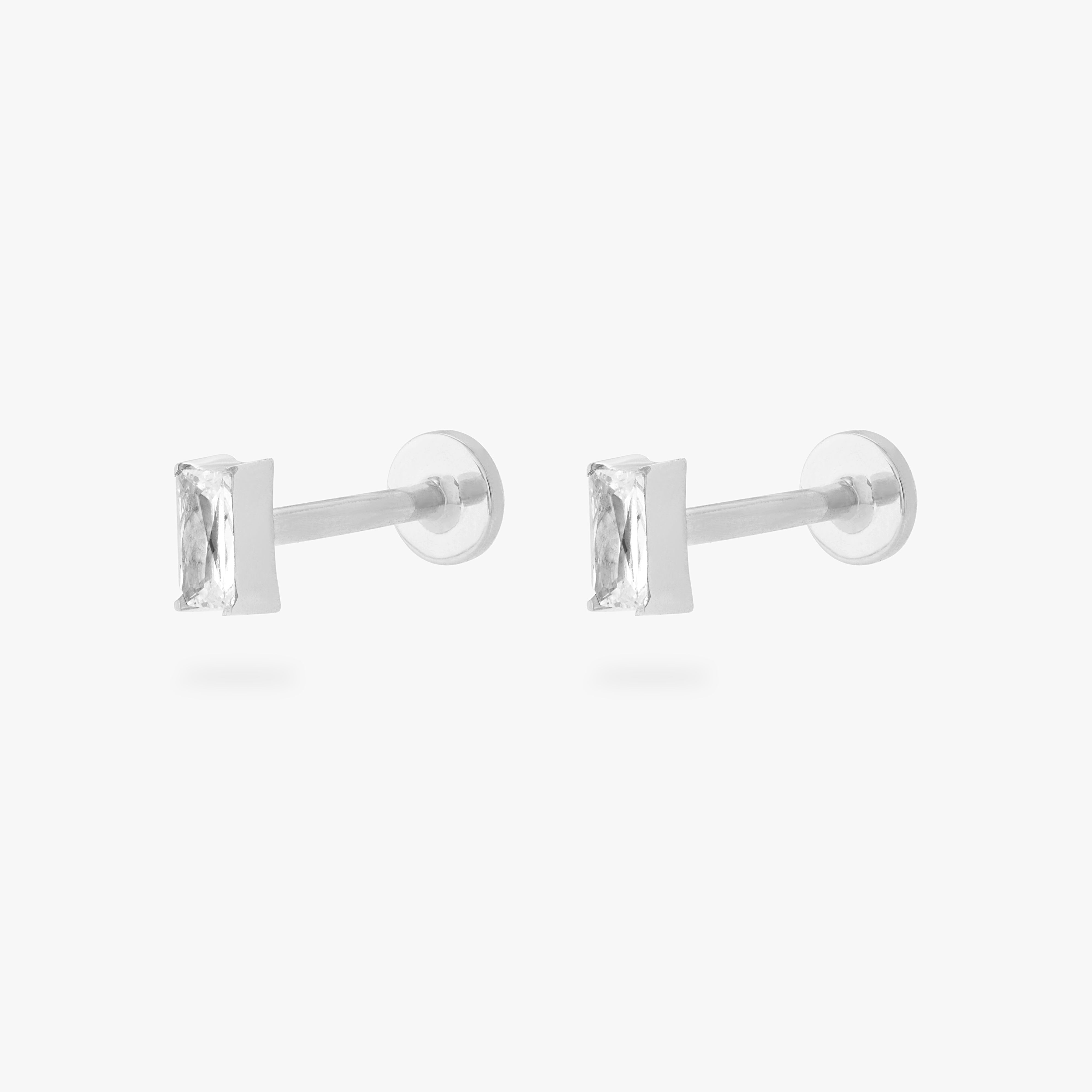 This is an image of a pair of silver/clear baguette shaped CZ flatback studs, with silver labrets with circle discs with "S" logos engraved on them. [pair] color:null|silver/clear