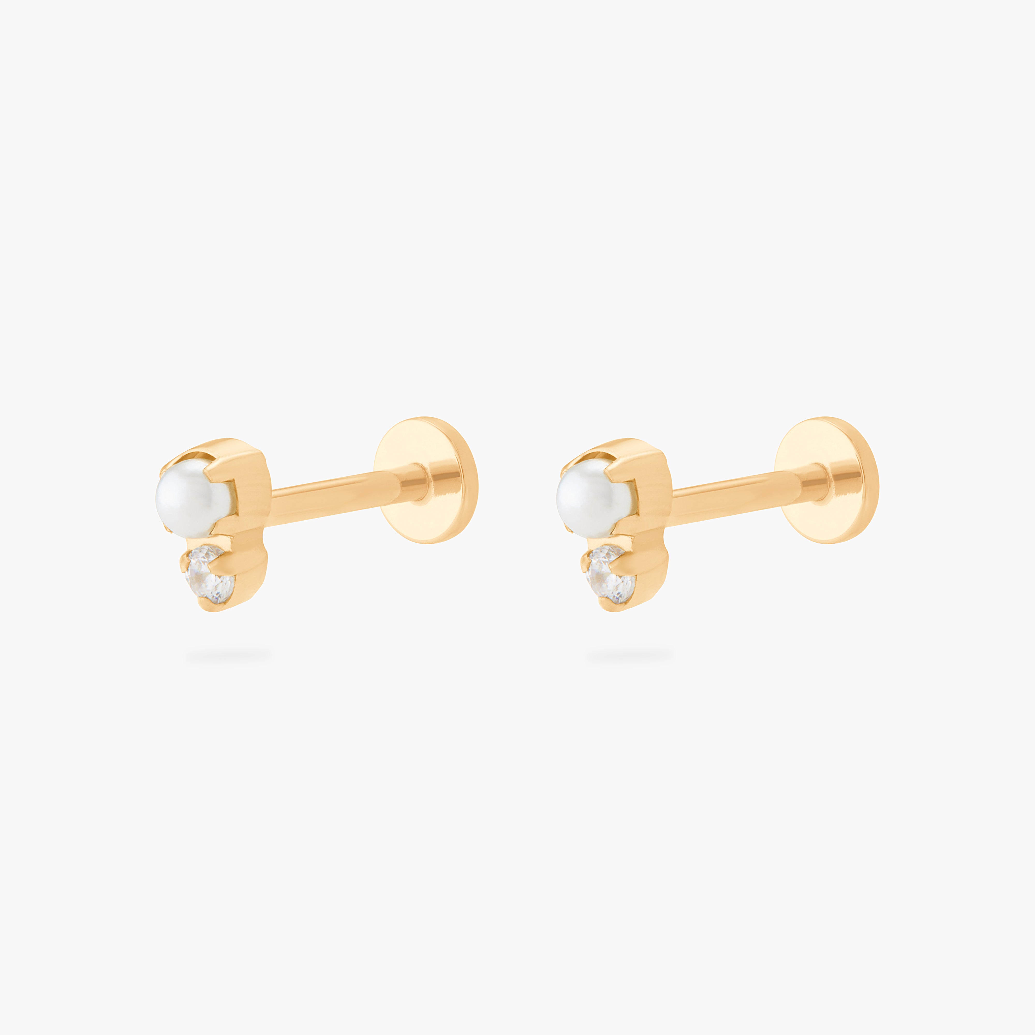 This is an image of a pair of flatback tops which have a pearl stacked over gold/clear CZs and then gold labrets that have circle discs with the "S" logo engraved on them. [pair] color:null|gold/clear
