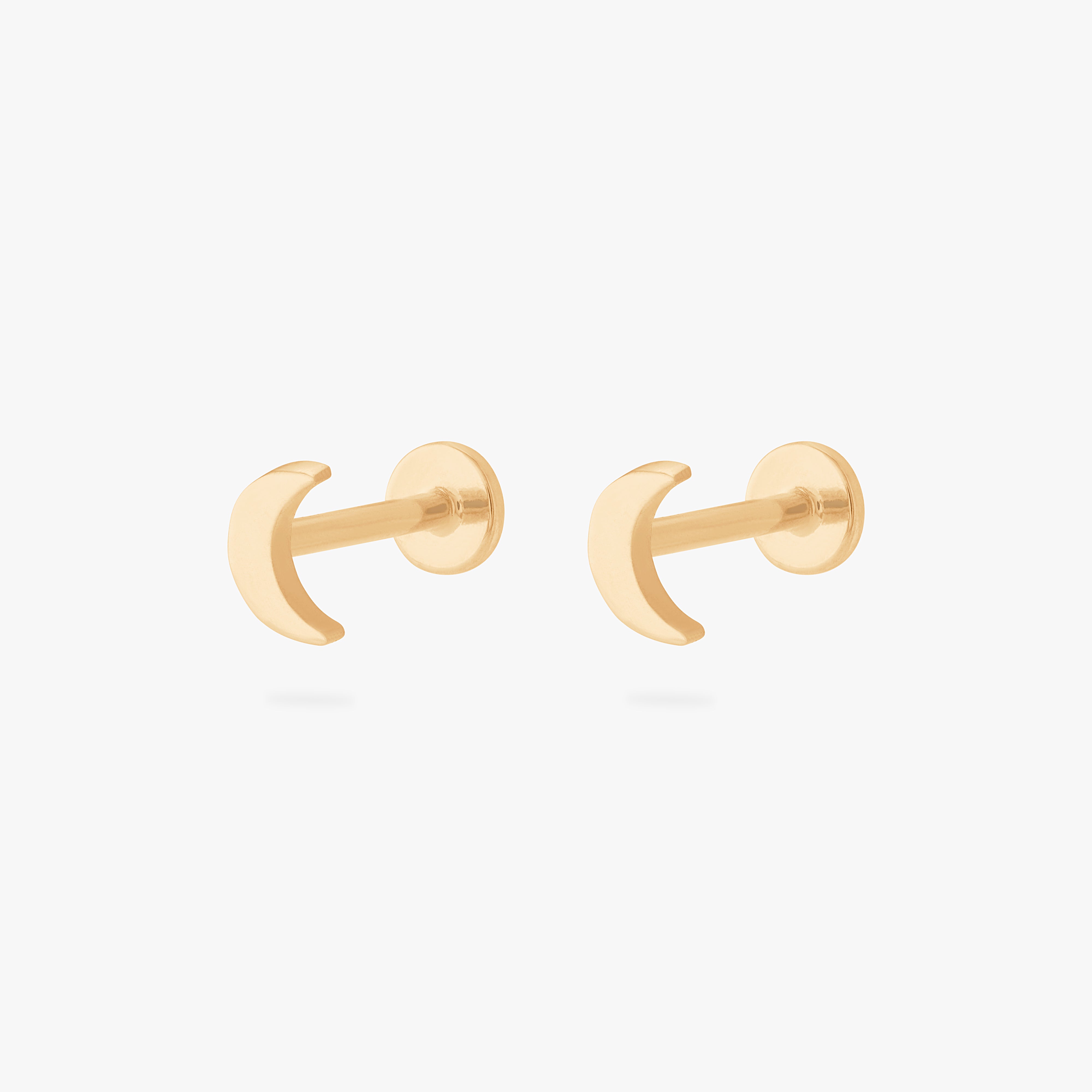 This is an image of a pair of gold moon shaped flatback tops with gold labrets with circle discs with the "S" logo engraved in them. [pair] color:null|gold/clear|gold