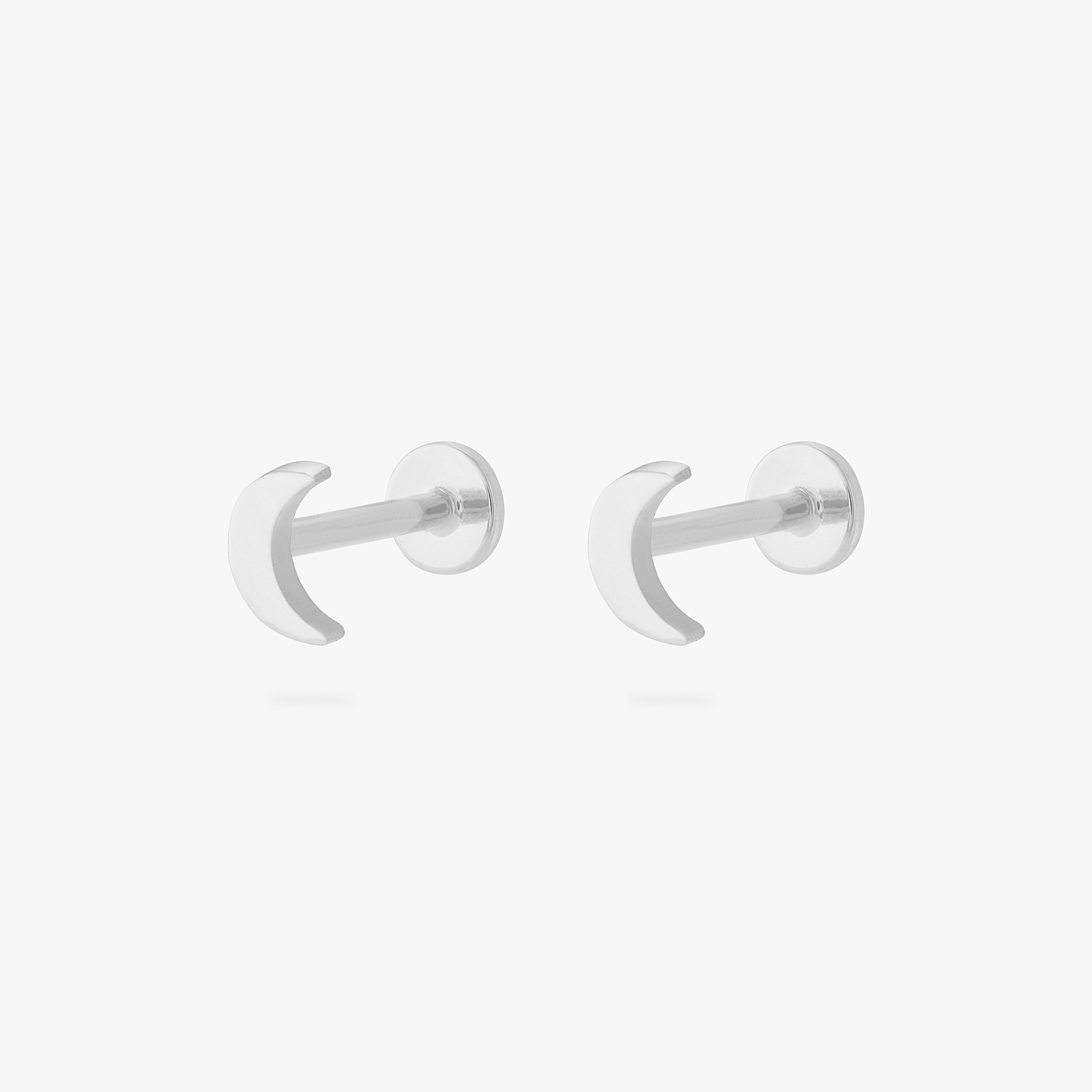 This is an image of a pair of silver moon shaped flatback tops with silver labrets with circle discs with the "S" logo engraved in them. [pair] color:null|silver/clear|silver