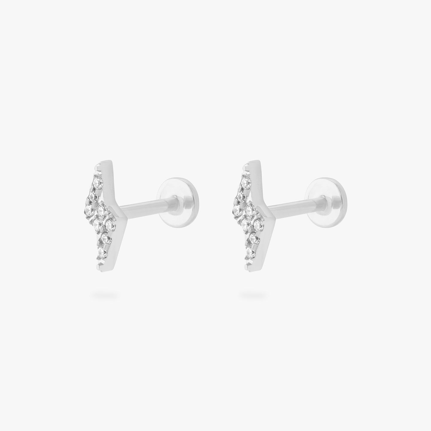 This is an image of a pair of silver/clear pave lightning-bolt shaped flatback tops with silver labrets with circle discs that have an 
