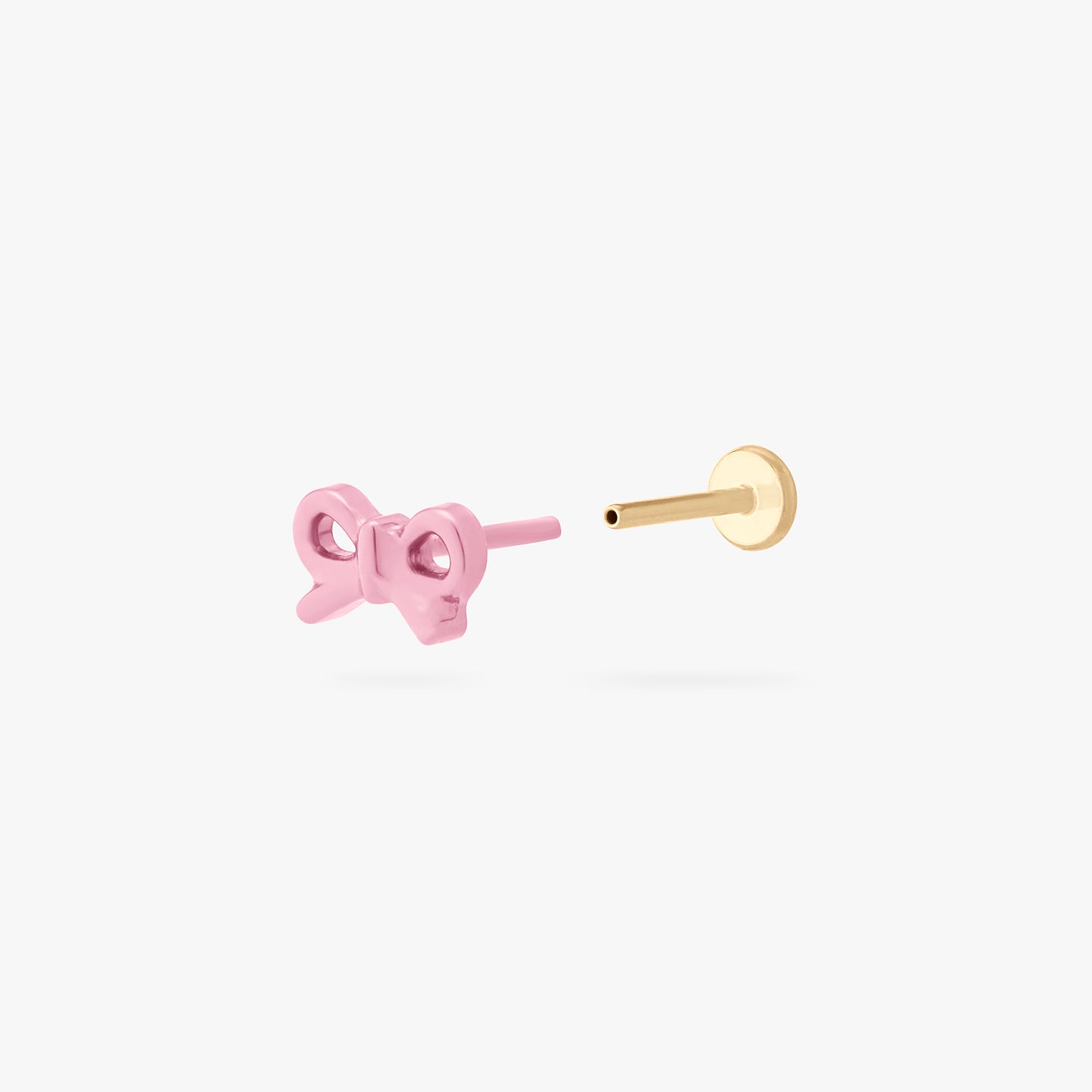 This image is of a pink bow-shaped flatback stud made out of titanium with a gold-toned labret back removed. color:null|pink