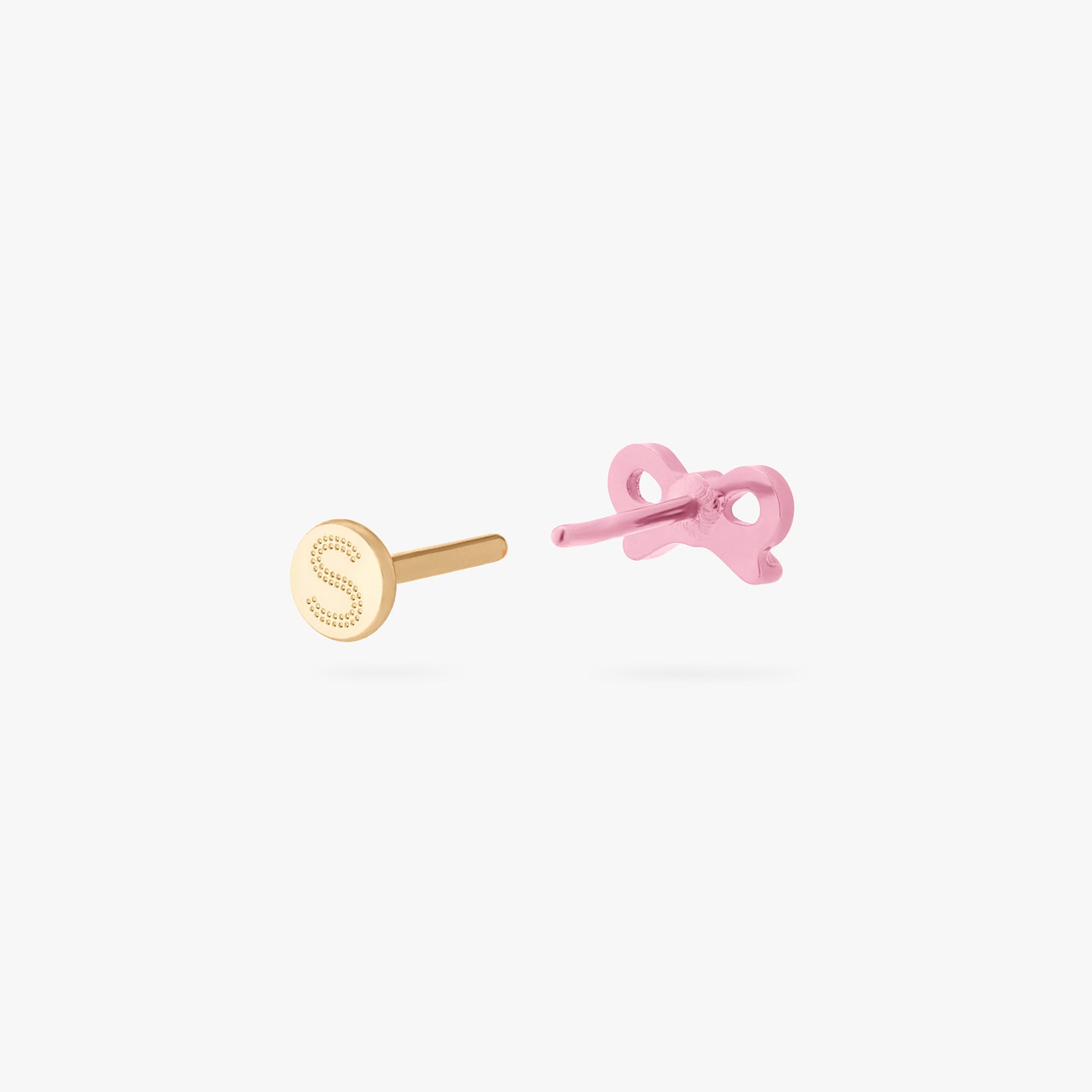 This image is of a pink bow-shaped flatback stud made out of titanium with a gold-toned labret back removed facing opposite of the camera. color:null|pink