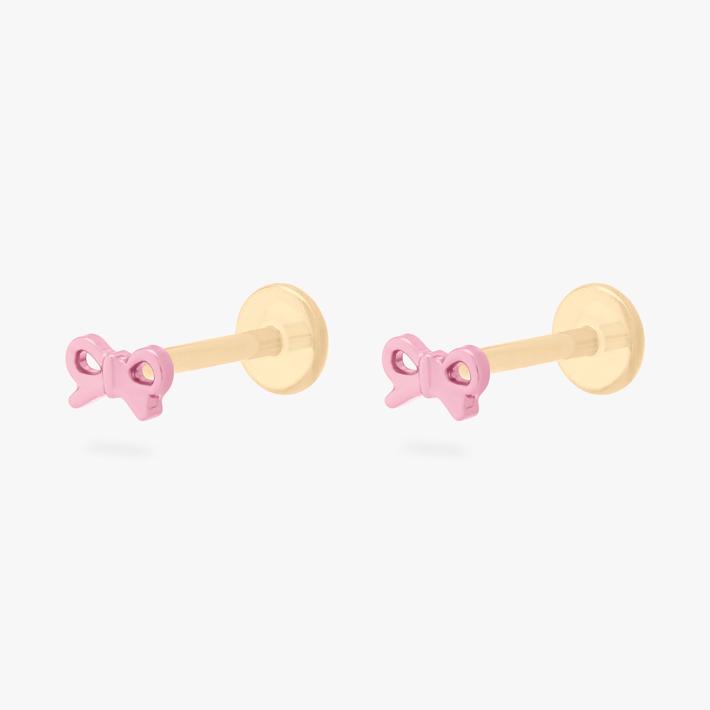 This image is of a pair of pink bow-shaped flatback studs made out of titanium with gold-toned labret backs on. [pair] color:null|pink