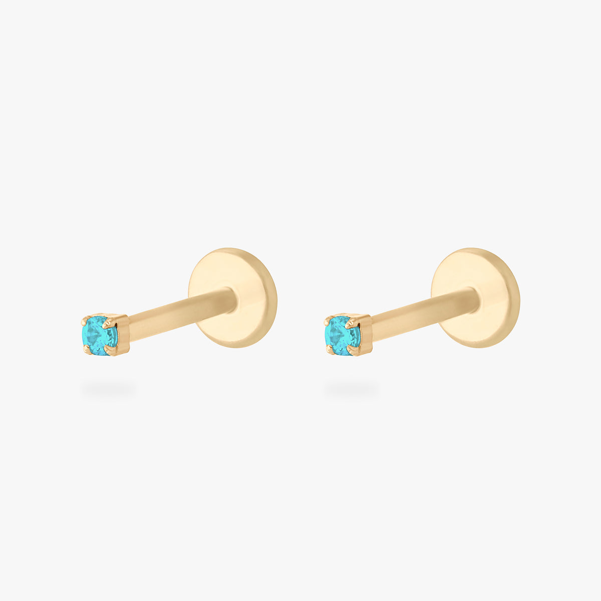 Pair of gold micro CZ flatback stud earrings with small light blue cz stones in prong setting displayed side by side