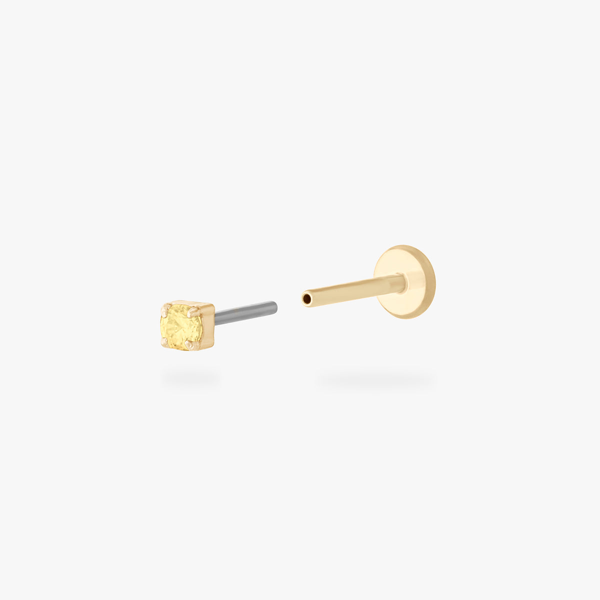 Gold micro CZ flatback stud earring with small yellow stone in prong setting shown from side angle