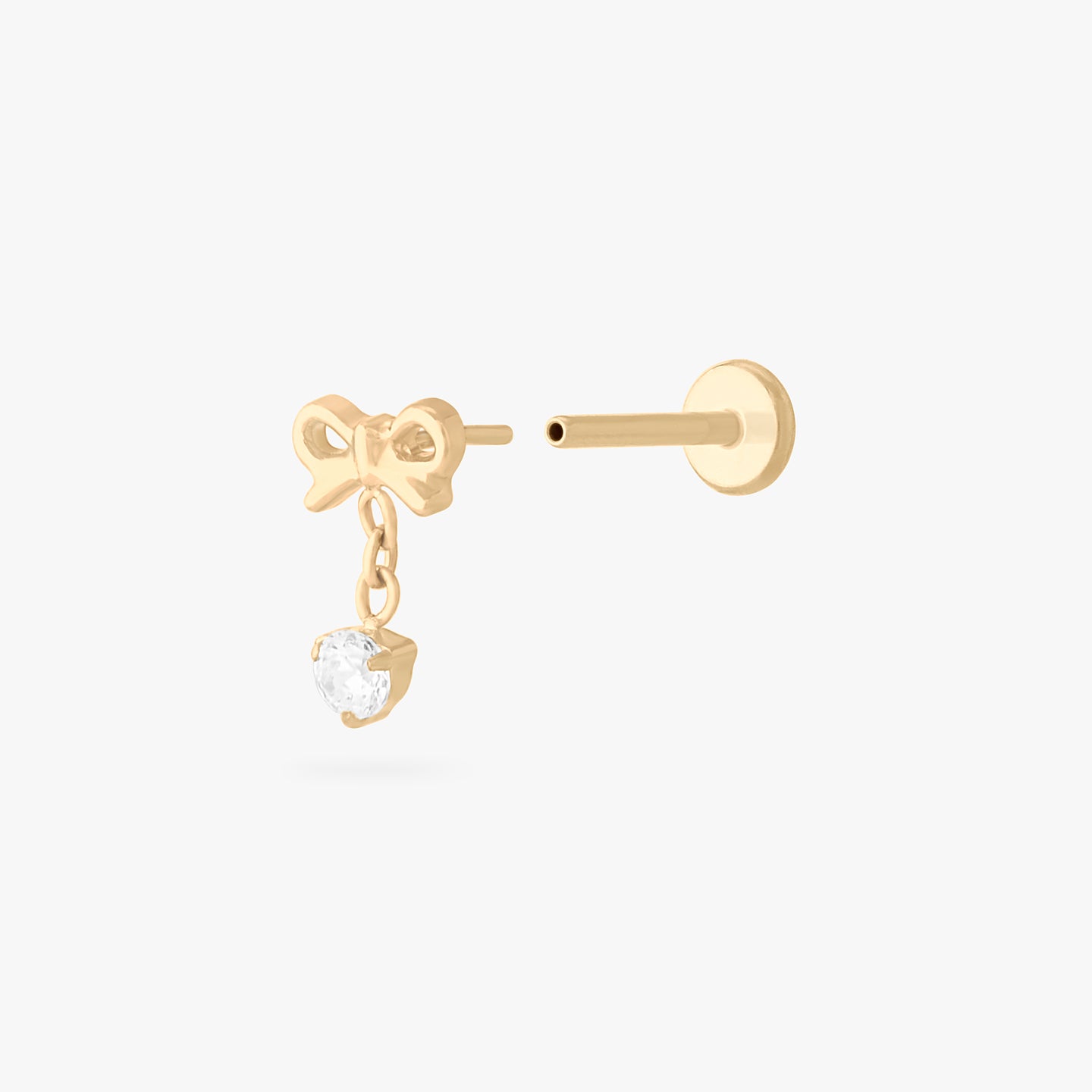 This is an image of a gold-toned flatback stud with a bow that a chain with a CZ dangles from. color:null|gold/clear