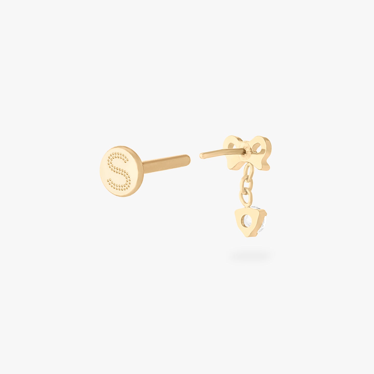 This is an image of a gold-toned flatback stud with a bow that a chain with a CZ dangles from. color:null|gold/clear