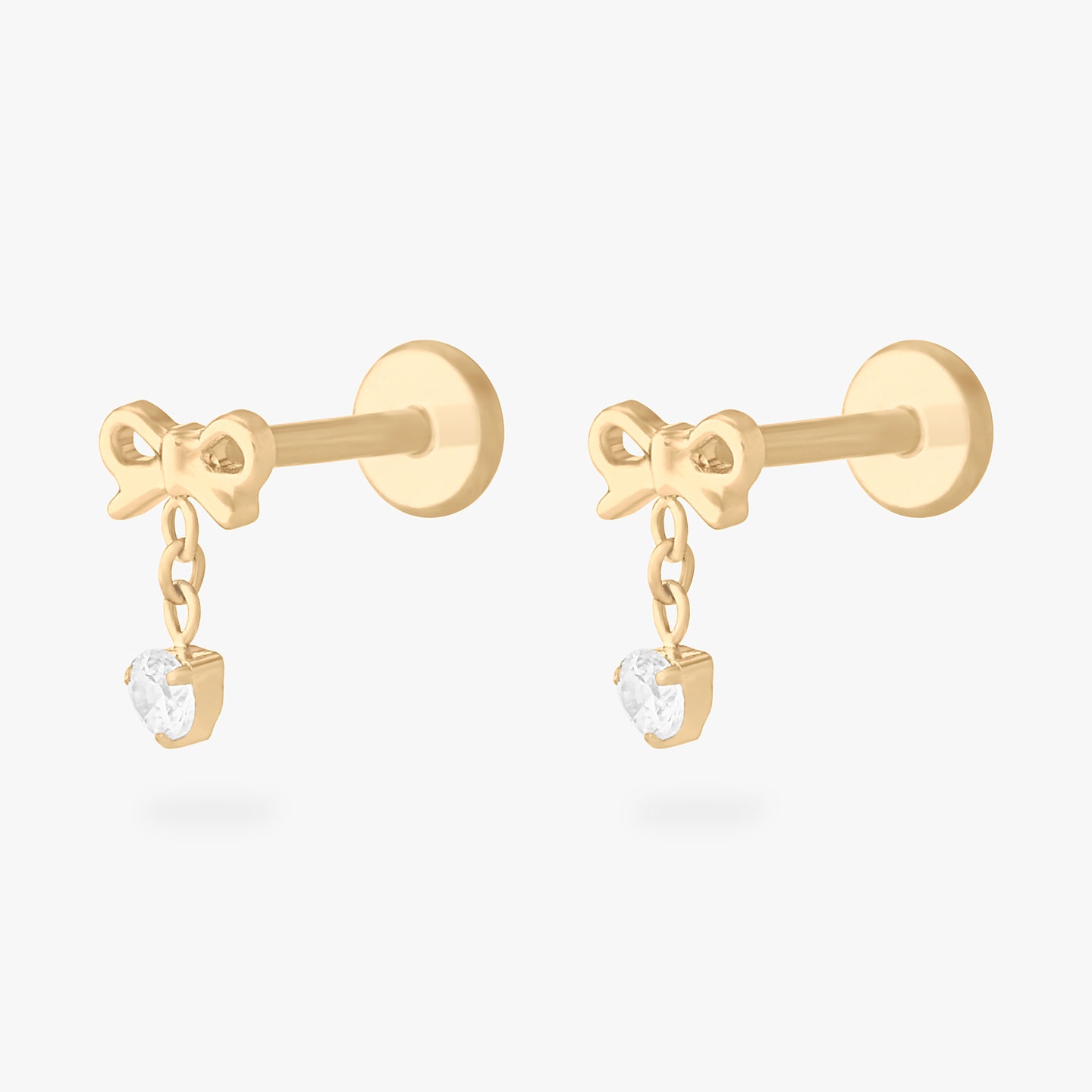 This is an image of a pair of gold-toned flatback studs with bows that chains with CZ's dangle from. [pair] color:null|gold/clear