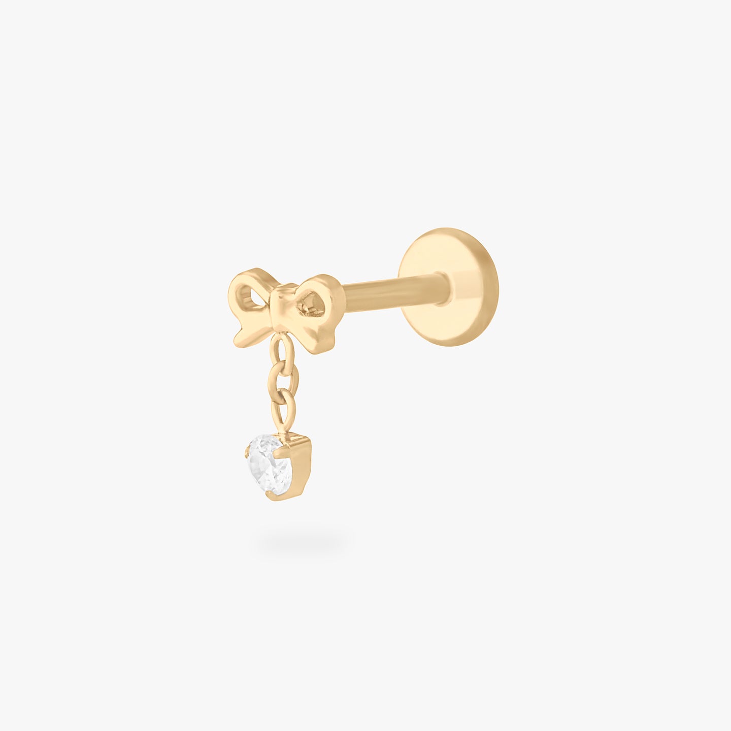 This is an image of a gold-toned flatback stud with a bow that a chain with a CZ dangles from. color:null|gold/clear