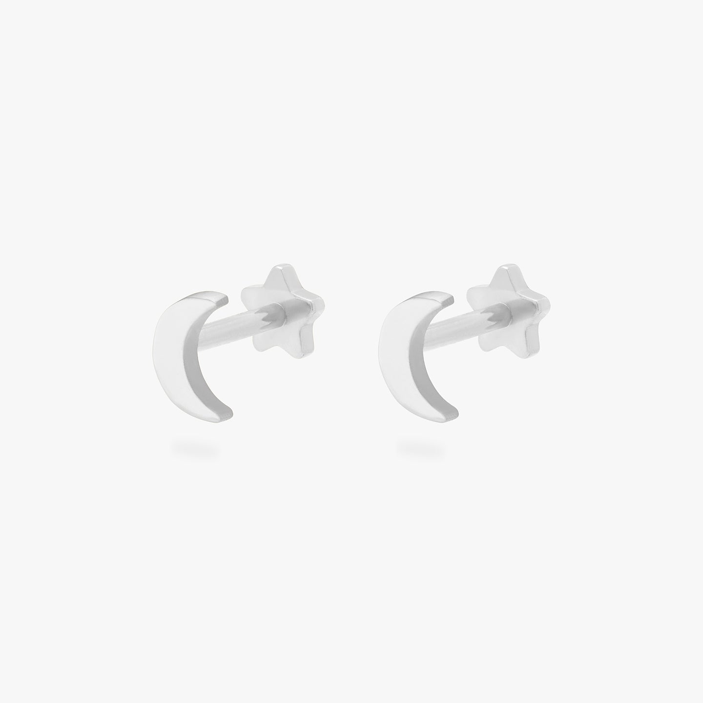 This is an image of a pair of silver moon-shaped flatback tops with silver labrets with star-shaped discs. [pair] color:null|silver