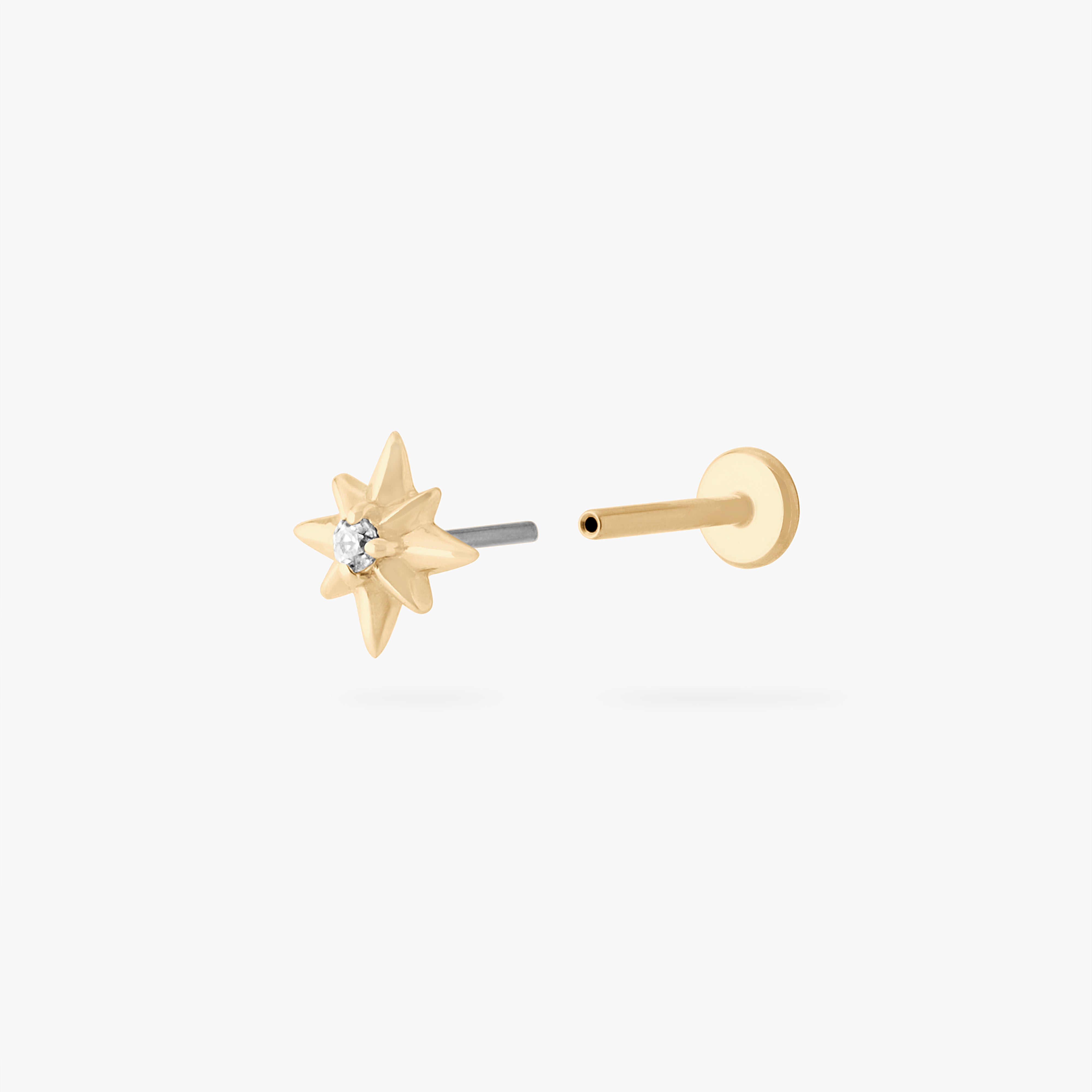 This is an image of a 14K gold flatback stud with a pointed star with a clear cz stone in the center. color:null|gold|gold/clear