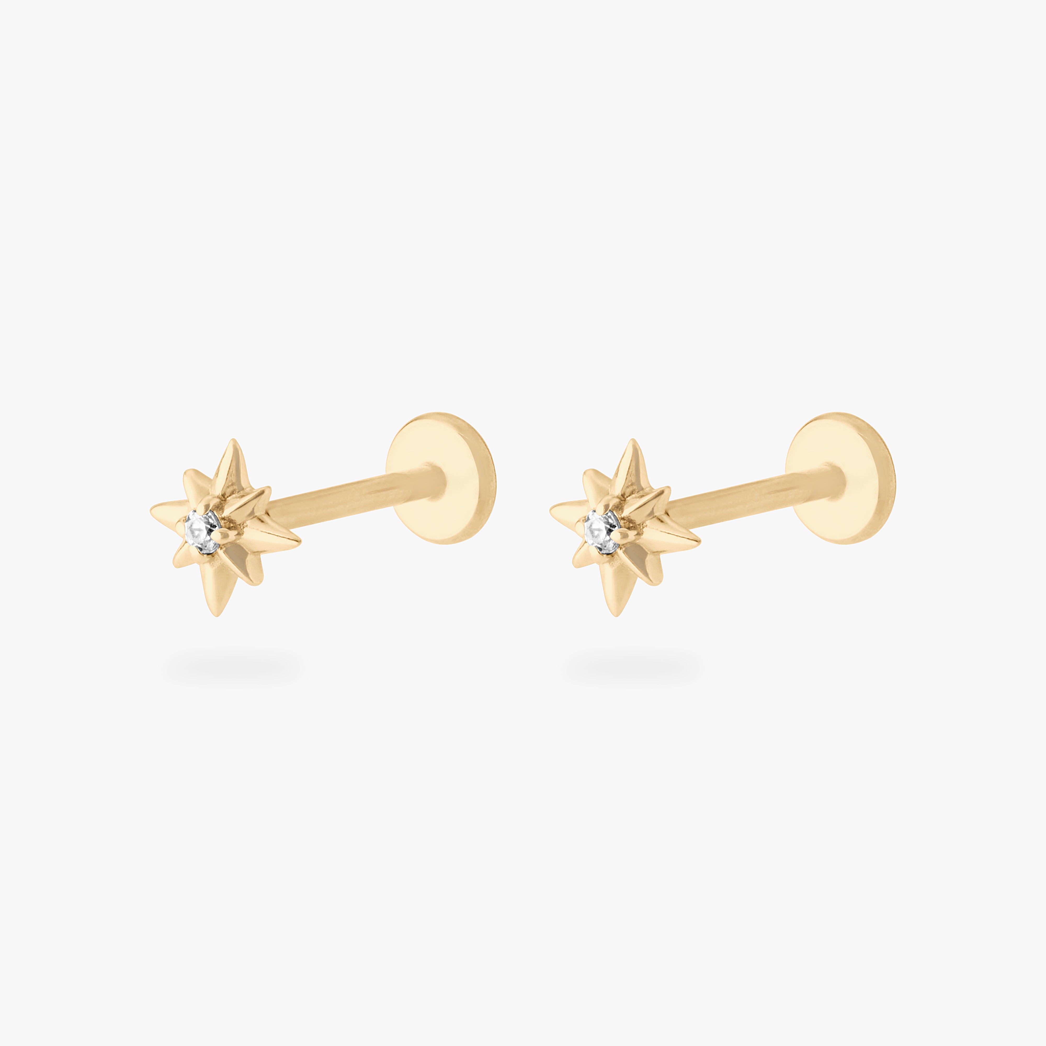 This is an image of a pair of 14K gold flatback studs with pointed stars with clear cz stones in the center. [pair] color:null|gold|gold/clear