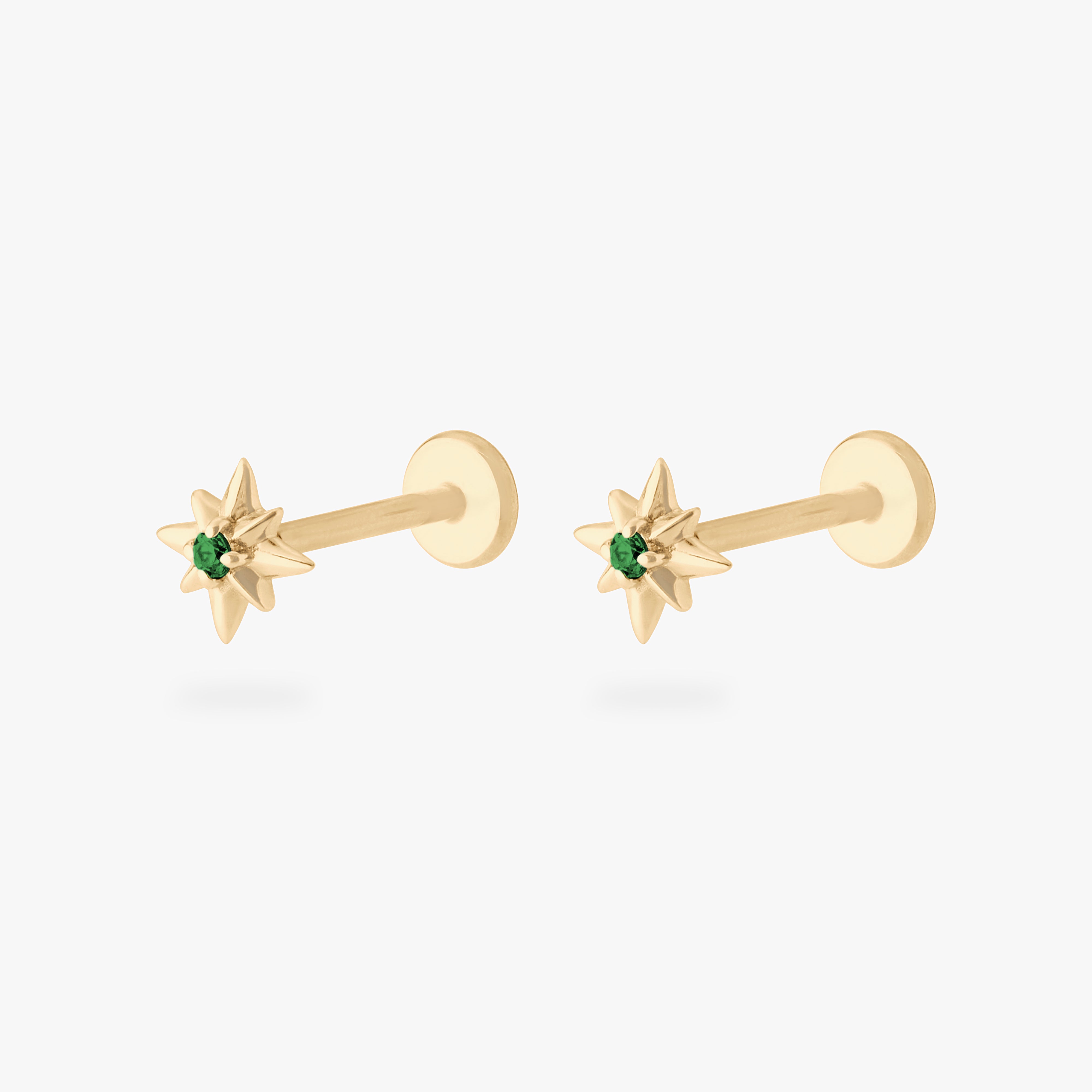 This is an image of a pair of 14K gold flatback studs with pointed stars with green cz stones in the center. [pair] color:null|gold/green