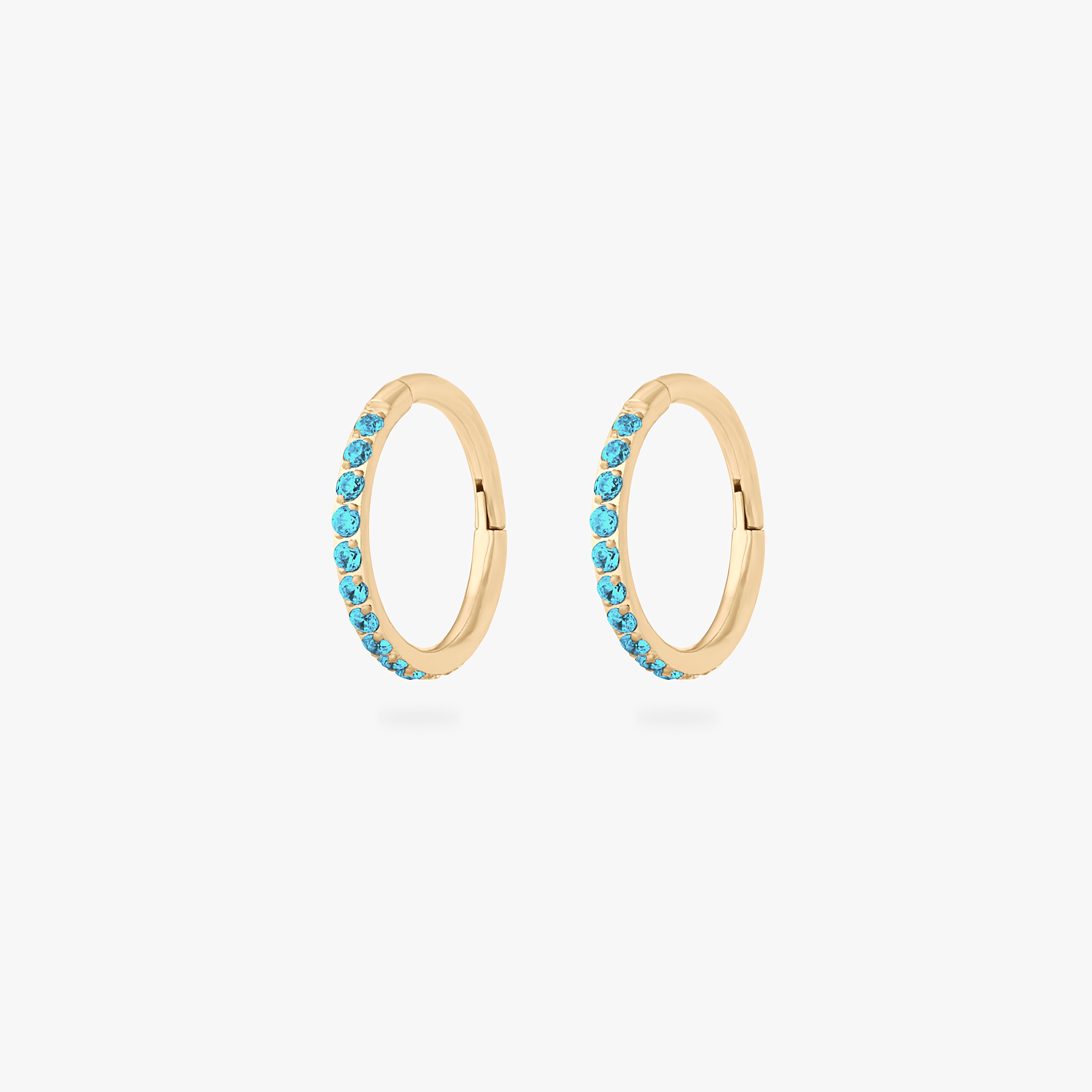 This is a pair of gold toned clickers with aquamarine cz stones. [pair] color:null|aquamarine