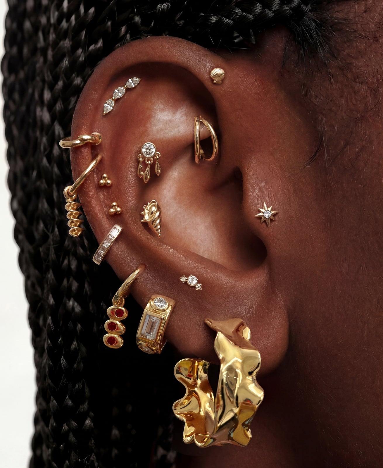 Close-up of an ear with multiple gold earrings against a blurred background