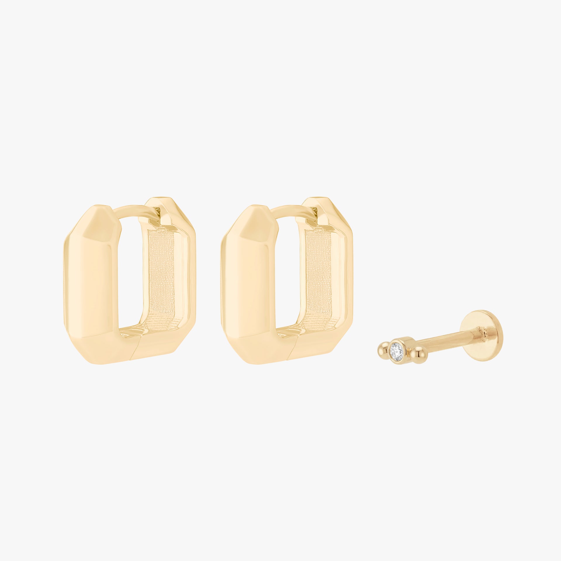 Gold earscape set with a pair of geometric huggies and a micro bezel flatback with a clear stone - Main view