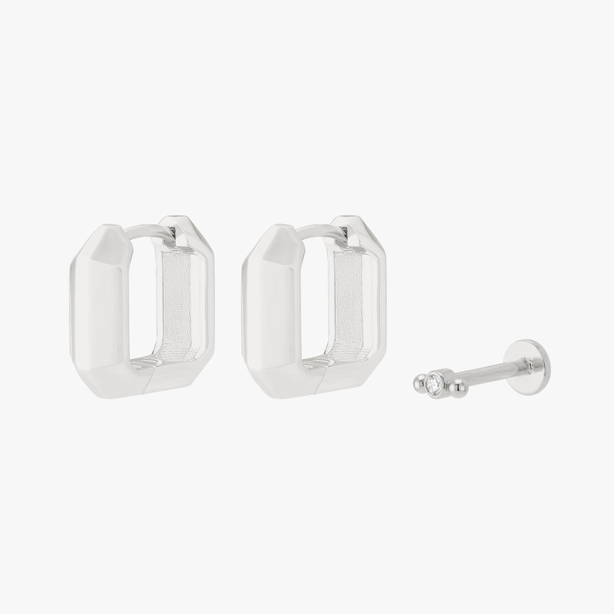 Silver earscape set with a pair of geometric huggies and a micro bezel flatback with a clear stone