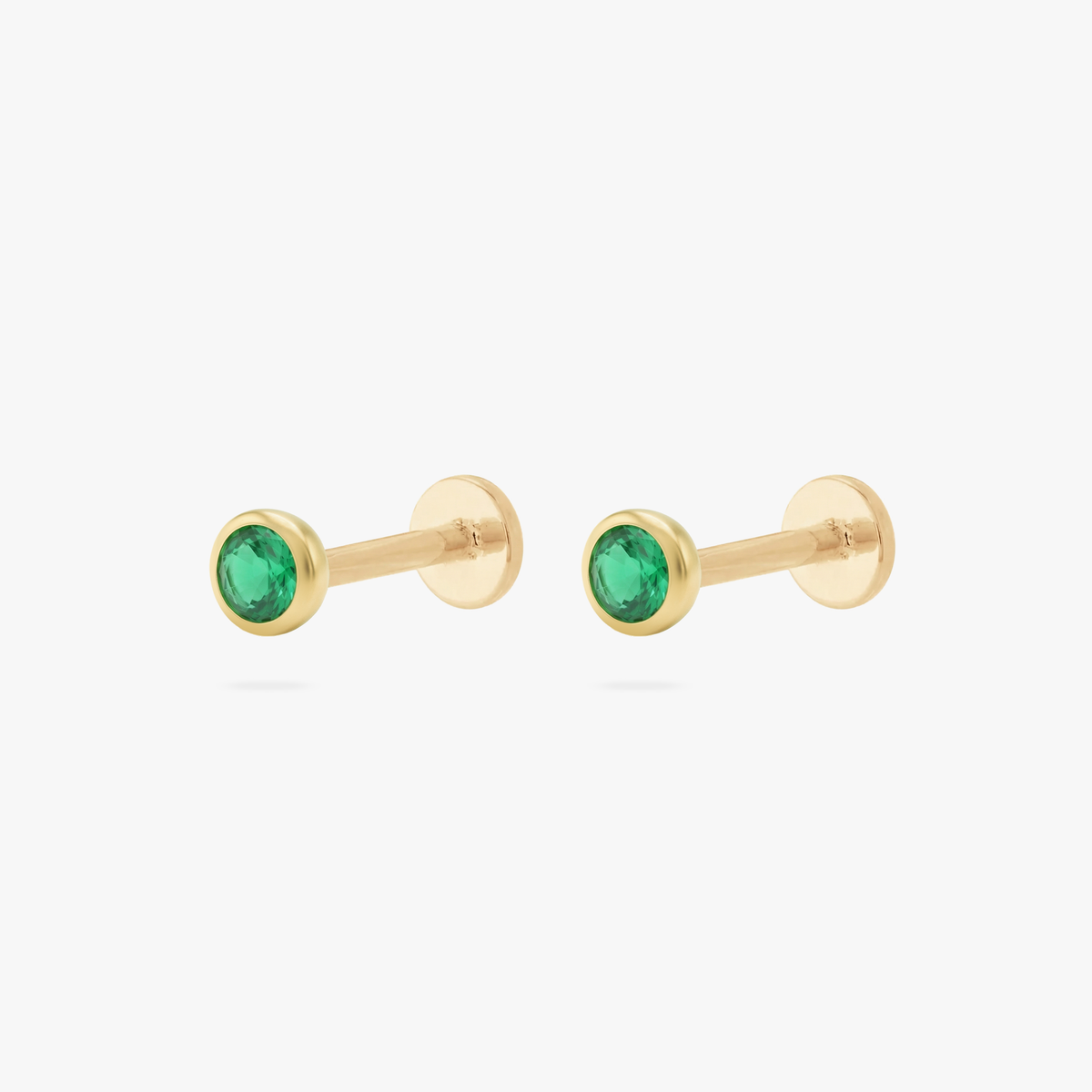 This is an image of a pair of gold toned flatback studs with 3mm, bezel set green CZ stones. 