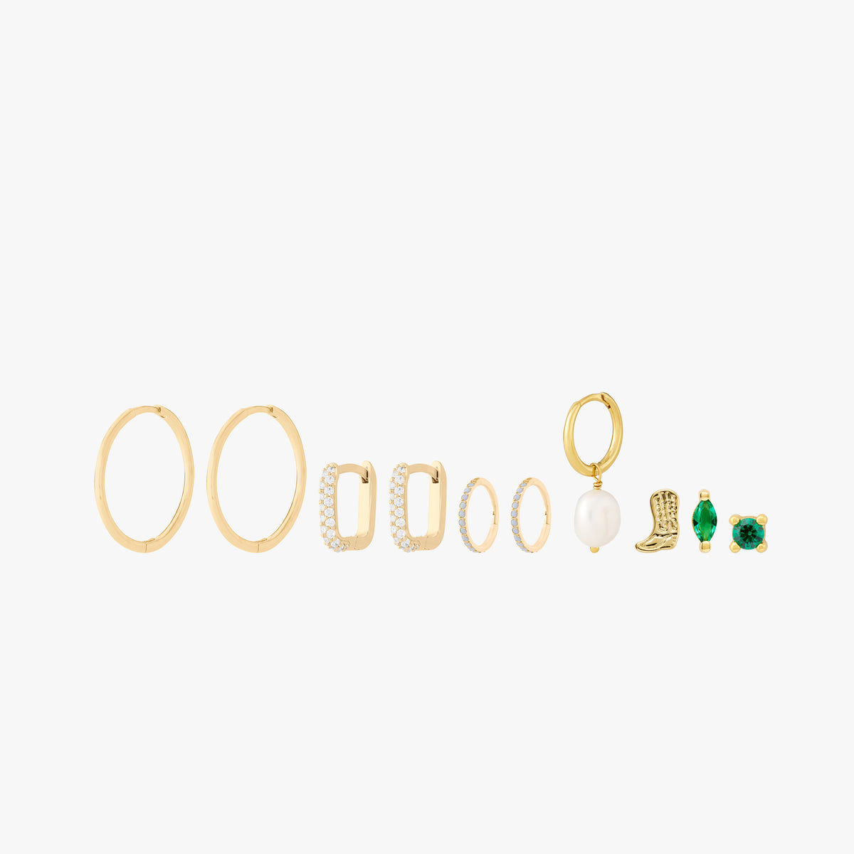 This image shows a set of 14k Yellow Gold plated earrings. The set includes one thin hoop pair, two pairs of huggies. One square shaped with clear cz stones and another with pearl cz stones. There is a singular open pearl huggie and three singular studs. There is a cowboy boot, a marquise with a green cz stone and a green cz stone stud flatback.