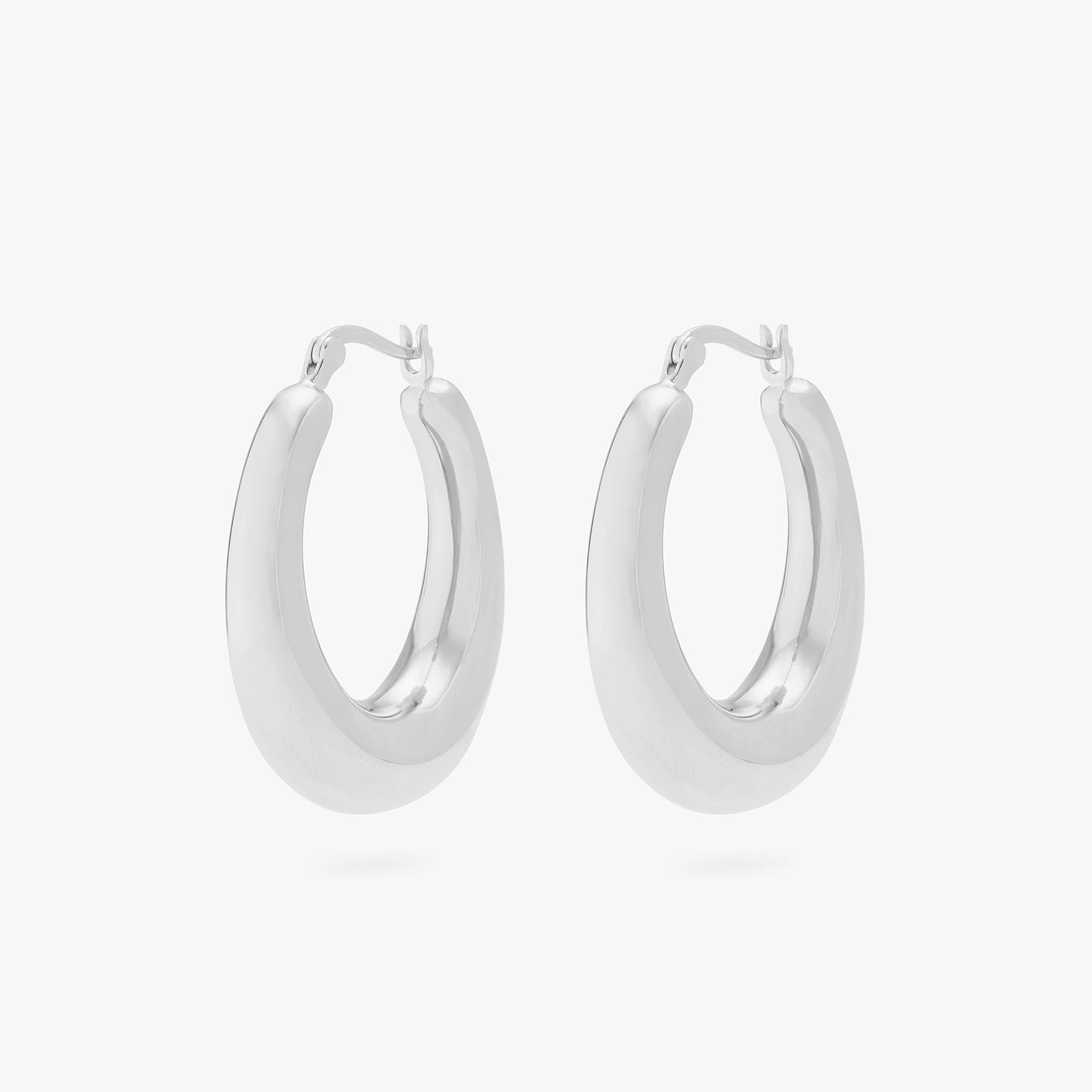 This is a pair of silver, medium-sized, oval crescent shaped hoops. [pair] color:null|silver