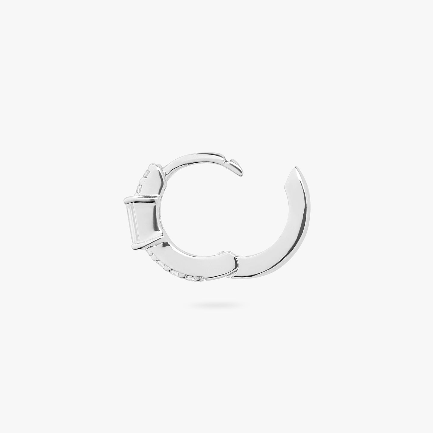 An image of a silver/clear huggie with a silver accent baguette CZ stone on ear. color:null|silver/clear