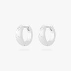 This is an image of a pair of silver-toned huggies with twinkle star shaped engravings with CZs in them. [pair] color:null|silver/clear