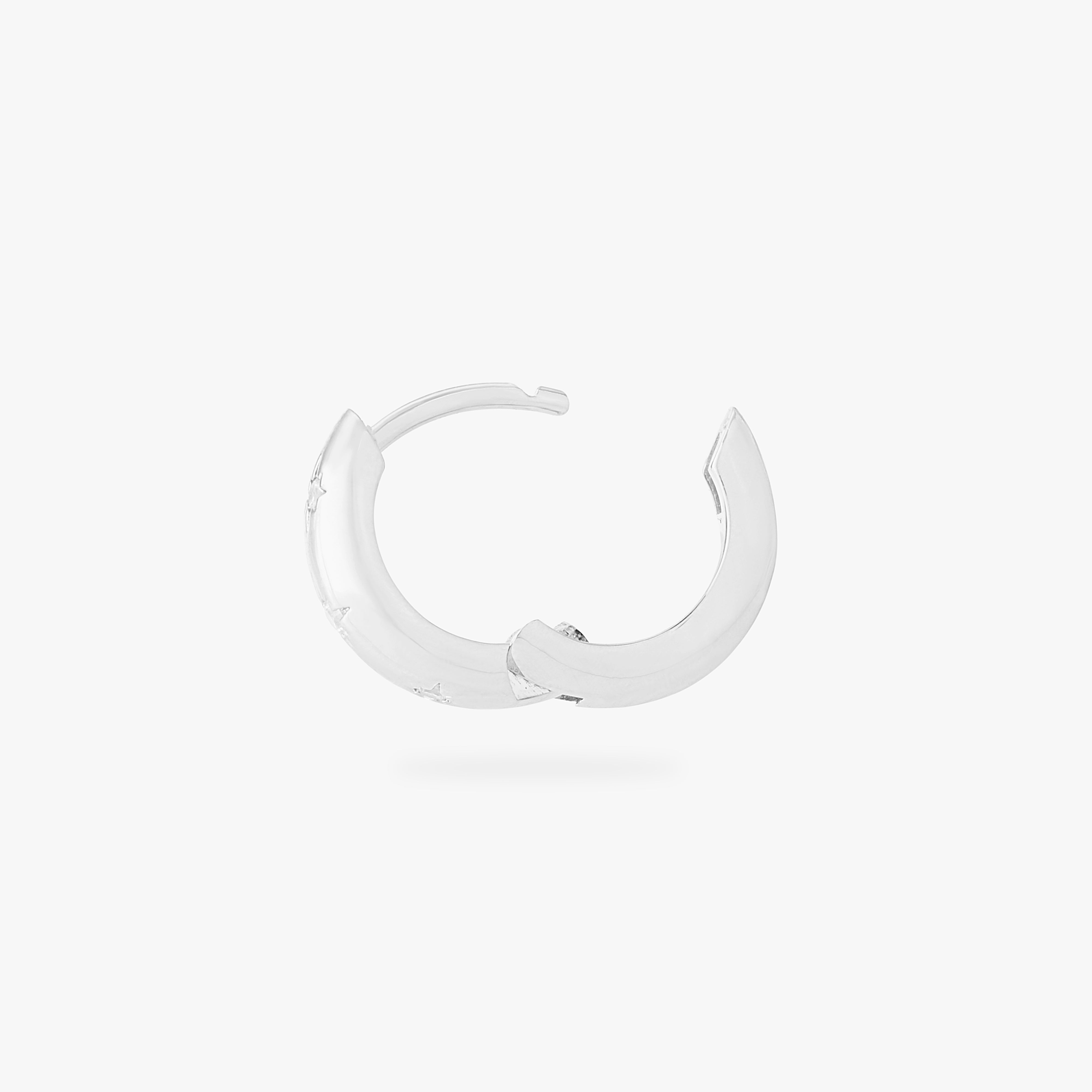 This is an image of a silver-toned huggie with twinkle star shaped engravings with CZs in them. color:null|silver/clear