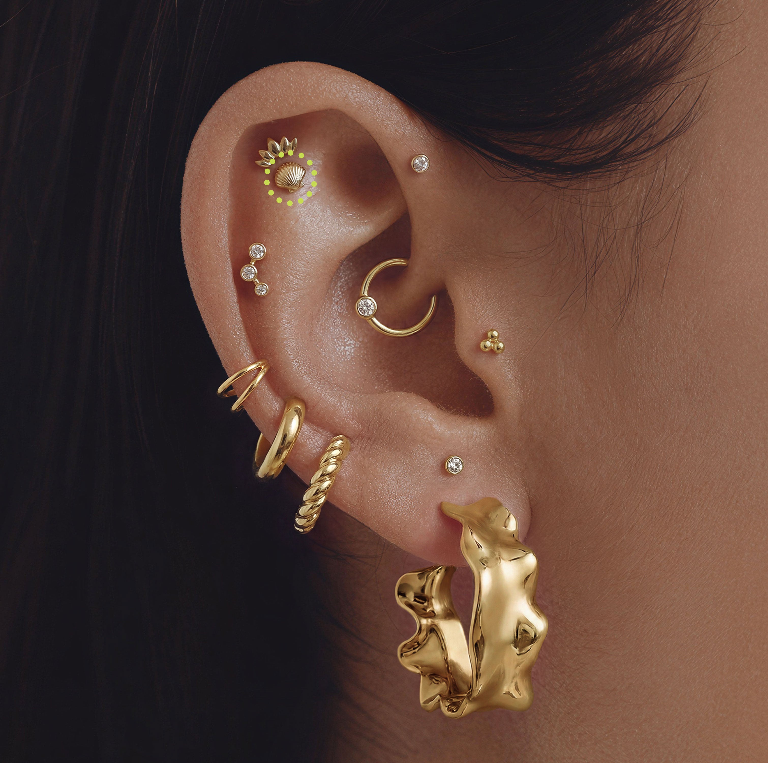 This is a close up image of an ear with a  14k gold shell flat back earring 