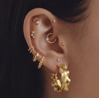 This image shows an ear with a organic shape 14k gold plated hoop 