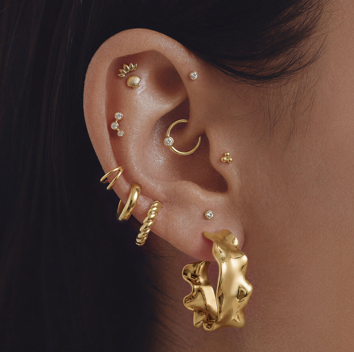 This image shows an ear with a organic shape 14k gold plated hoop 