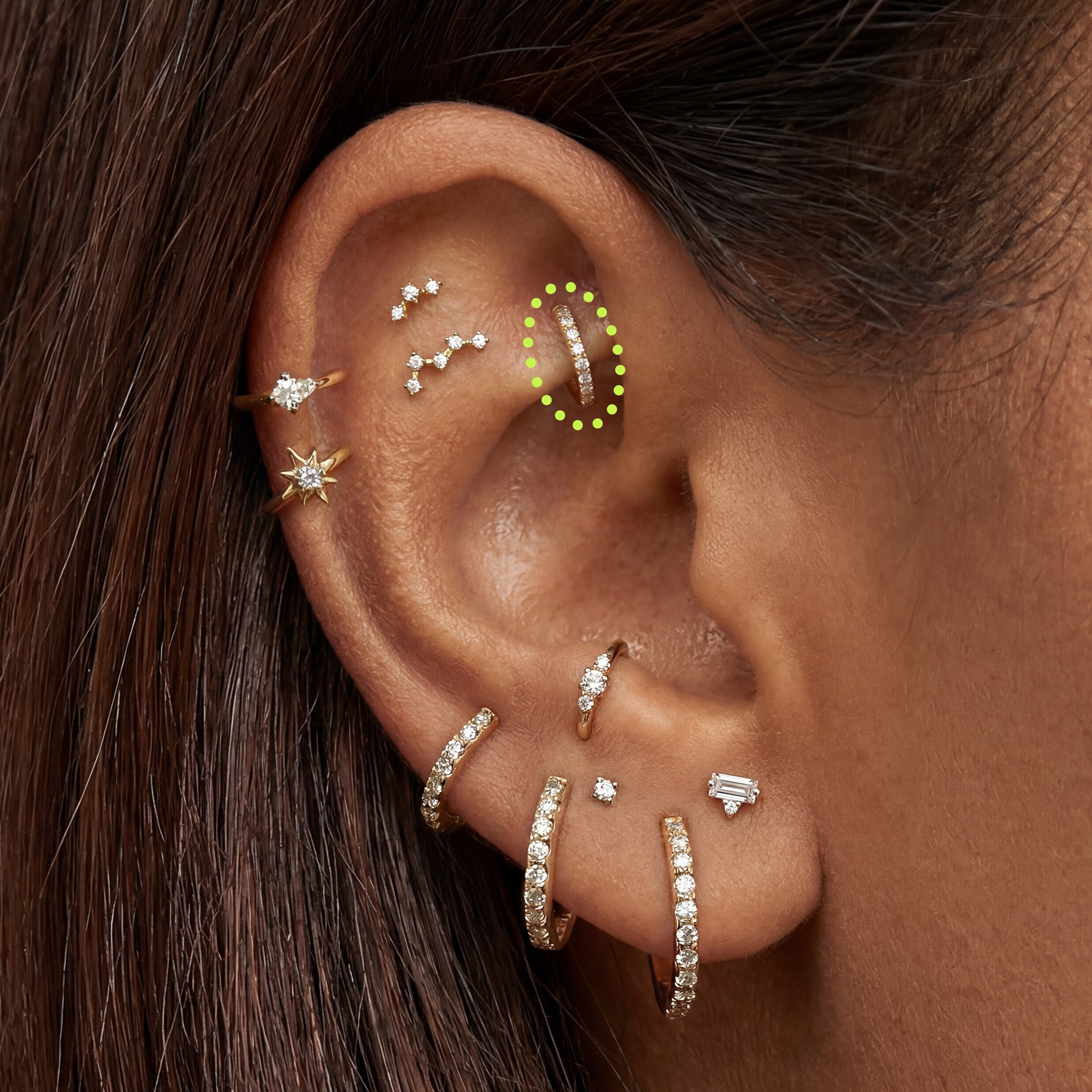 Close-up of an ear with multiple gold sparkly earrings with a 5mm pave clicker circled in the rook 