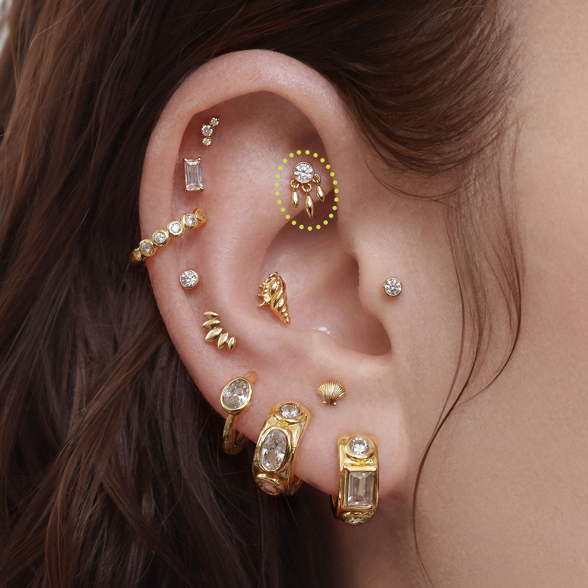 This is a close up image of an ear with a  14k gold fringe bezel flat back earring 
