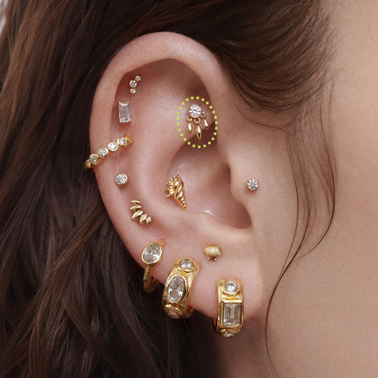 This is a close up image of an ear with a  14k gold fringe bezel flat back earring 