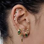 this image shows an ear with a 14k gold plated huggie with three green circular cz stones