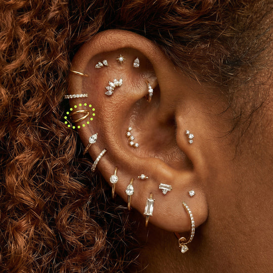 Close-up of an ear with multiple earrings  with a 5mm gold double clicker circled in the helix