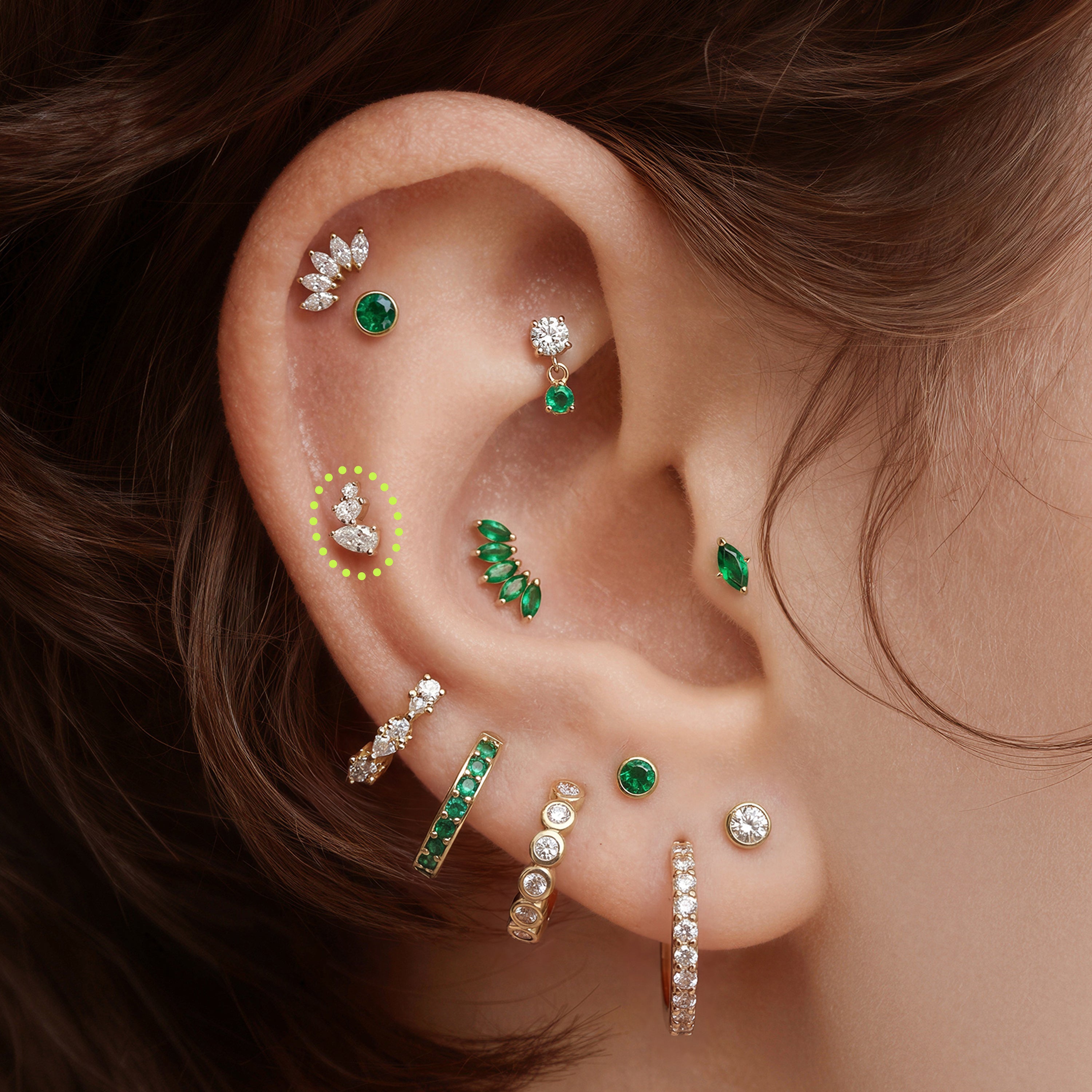 This is an image of a gold toned flatback stud with clear, pear cut CZs in a cluster circled on an ear.