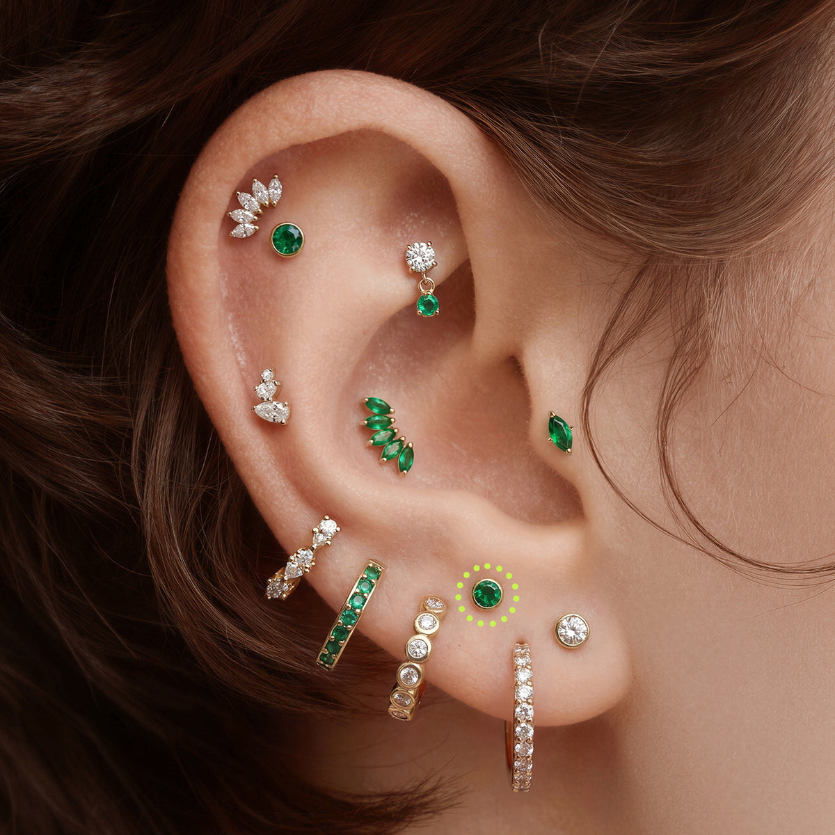 This is an image of a gold toned flatback stud with a 3mm, bezel set green CZ stone circled on an ear.