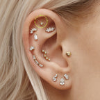 This is an image of a gold toned flatback stud which has a bar with chains from either side supporting a dangling twinkle star with a clear, round CZ center stone circled on an ear.