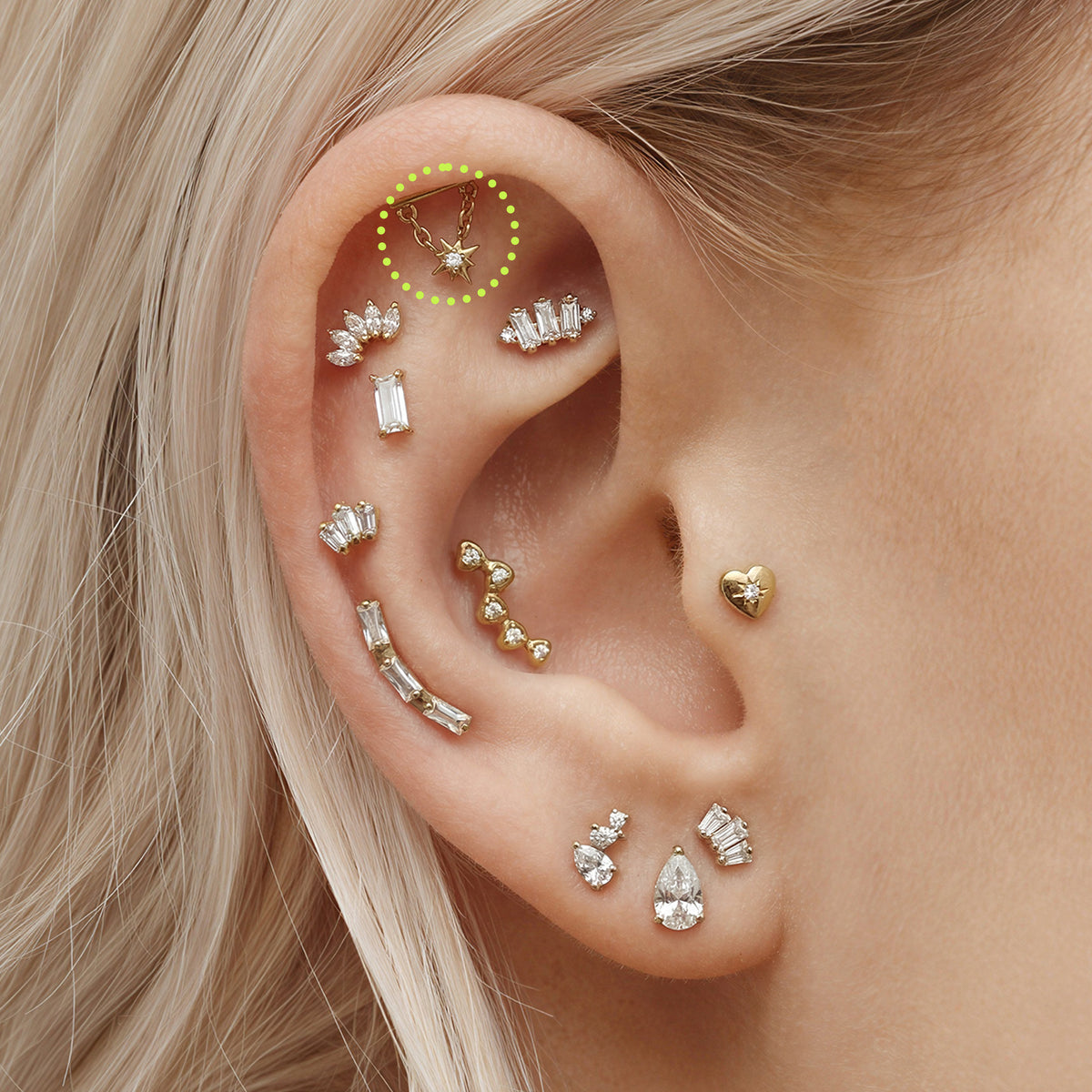 This is an image of a gold toned flatback stud which has a bar with chains from either side supporting a dangling twinkle star with a clear, round CZ center stone circled on an ear.