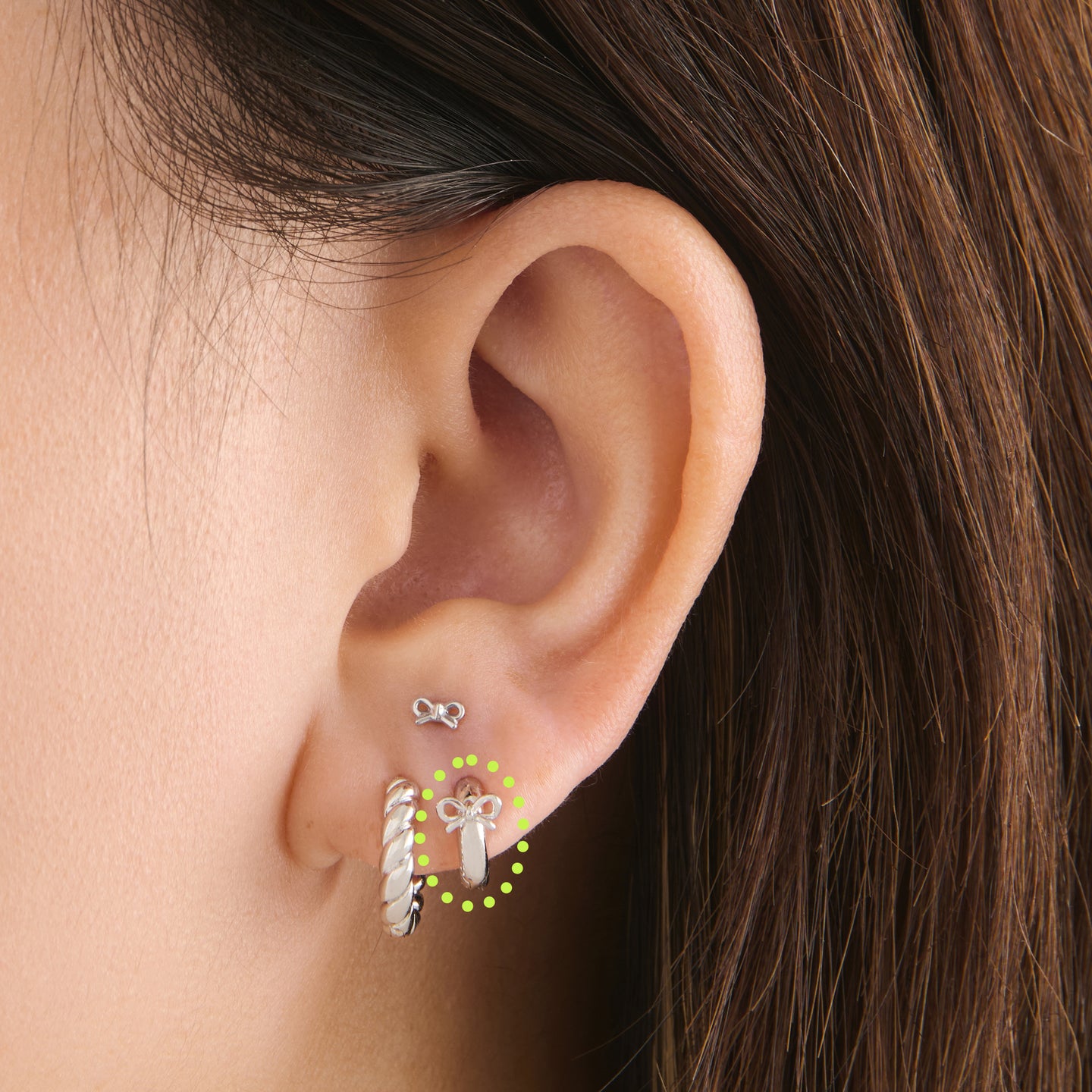 on ear featuring a micro huggie with a small bow accent in silver [hover] color:null|silver