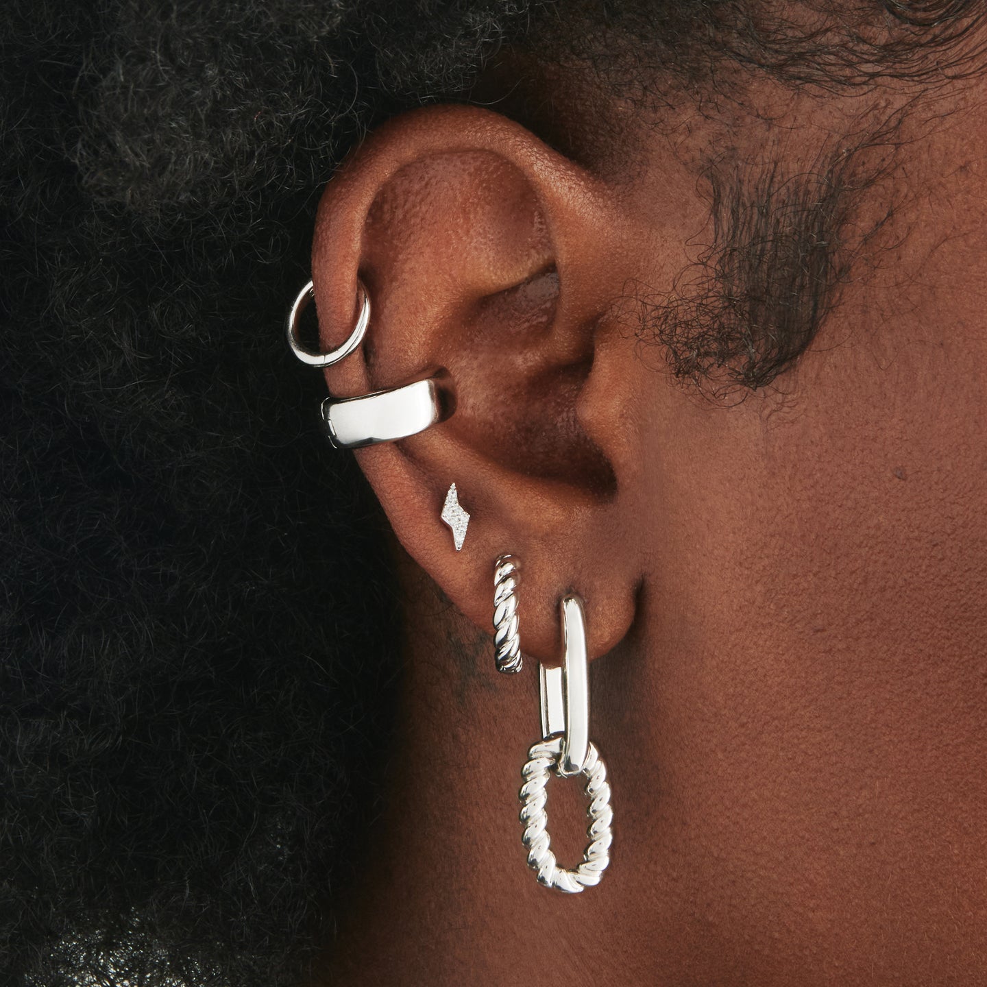 An image of a chunky silver twisted huggie on ear. [hover] color:null|silver