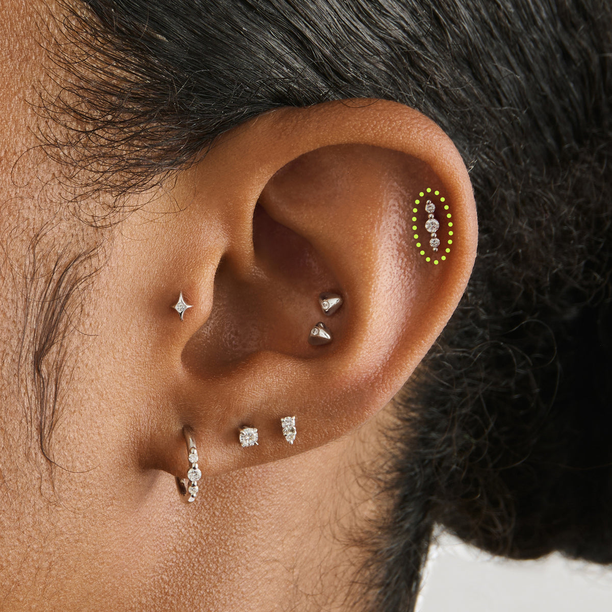 This image is a 14K white gold flatback stud that features 3 round diamonds with alternating 14K white gold spheres circled on an ear.