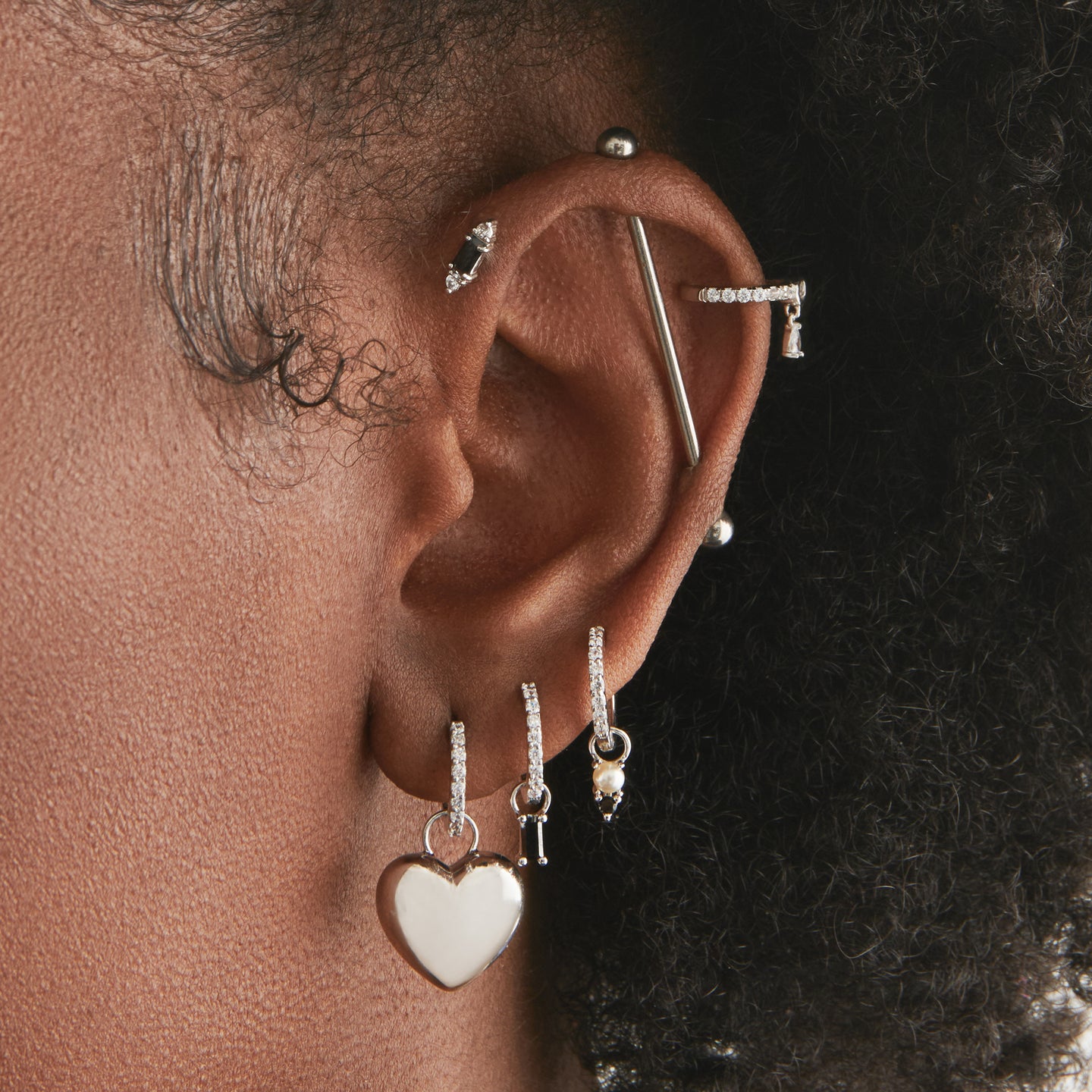 An image of a silver/clear mini pave huggie with a silver, puffy heart shaped charm on ear. [hover] color:null|silver/clear