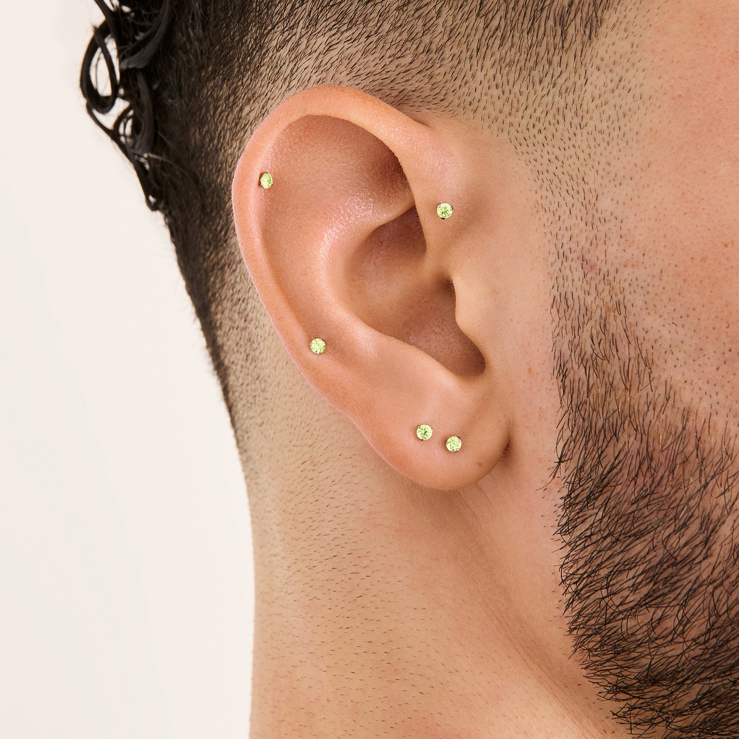 This image is a silver toned titanium flatback stud with a peridot cz stone on ear. [hover] color:null|peridot