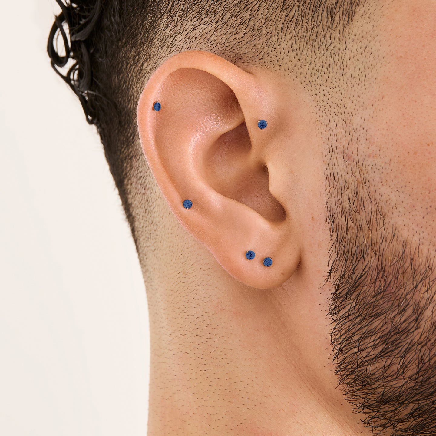 This image is a silver toned titanium flatback stud with a sapphire cz stone on ear. [hover] color:null|sapphire